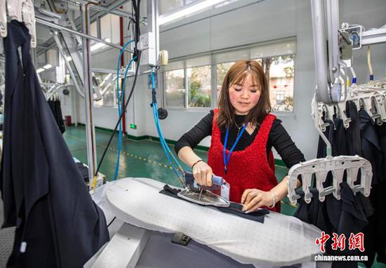 图为2月24日,工人在贵州省黔西市经济开发区一家服饰企业车间熨烫裁片。史开心 摄 图为2月24日,工人在贵州省黔西市经济开发区一家服饰企业车间熨烫裁片。史开心 摄