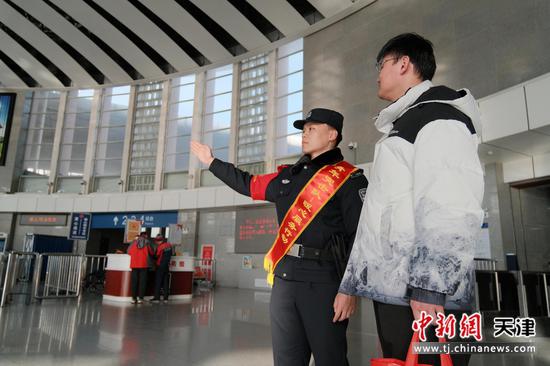 图为天津公安处青年突击队民警,正抬手为身旁的旅客清晰指引方向,用专业与耐心,为春运中的旅客提供精准指引,让返乡之路更顺畅、更安心。(北京铁路公安局天津公安处供图)