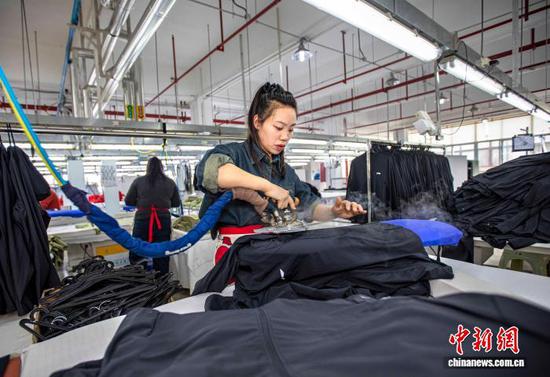 图为2月24日,工人在贵州省黔西市经济开发区一家服饰企业车间熨烫服饰。史开心 摄 图为2月24日,工人在贵州省黔西市经济开发区一家服饰企业车间熨烫服饰。史开心 摄