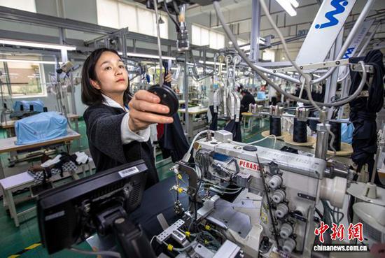 图为2月24日,工人在贵州省黔西市经济开发区一家服饰企业车间生产线上加工服饰。史开心 摄 图为2月24日,工人在贵州省黔西市经济开发区一家服饰企业车间生产线上加工服饰。史开心 摄