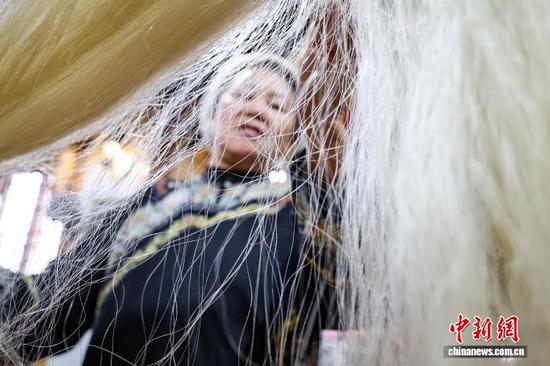 3月1日，韦桃花在整理马尾。水族马尾绣是贵州省黔南州三都水族自治县水族妇女世代传承的一种特殊刺绣技艺，被称为中国刺绣的“活化石”。马尾绣以丝线缠裹马尾并盘在描绘好的花纹轮廓上，再根据轮廓线绣出各种图案，工艺独特、复杂。62岁的韦桃花从小学习马尾绣制作技艺，是中国国家级非物质文化遗产水族马尾绣代表性传承人。50多年来，韦桃花在研究和继承传统马尾绣制作方法的基础上大胆创新，在图案设计、刺绣等工艺方面形成自己独有的制作风格，创作出一批精美独特的马尾绣作品深受消费者喜爱。中新社记者 瞿宏伦 摄