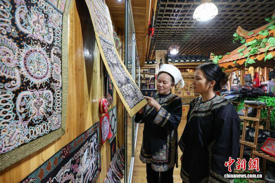 3月1日，韦桃花（左）在给儿媳覃毅柔讲解马尾绣背带制作技艺。水族马尾绣是贵州省黔南州三都水族自治县水族妇女世代传承的一种特殊刺绣技艺，被称为中国刺绣的“活化石”。马尾绣以丝线缠裹马尾并盘在描绘好的花纹轮廓上，再根据轮廓线绣出各种图案，工艺独特、复杂。62岁的韦桃花从小学习马尾绣制作技艺，是中国国家级非物质文化遗产水族马尾绣代表性传承人。50多年来，韦桃花在研究和继承传统马尾绣制作方法的基础上大胆创新，在图案设计、刺绣等工艺方面形成自己独有的制作风格，创作出一批精美独特的马尾绣作品深受消费者喜爱。中新社记者 瞿宏伦 摄