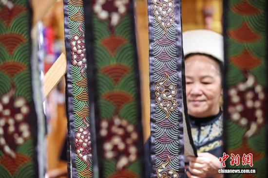 3月1日，韦桃花在整理缝制的马尾绣作品。水族马尾绣是贵州省黔南州三都水族自治县水族妇女世代传承的一种特殊刺绣技艺，被称为中国刺绣的“活化石”。马尾绣以丝线缠裹马尾并盘在描绘好的花纹轮廓上，再根据轮廓线绣出各种图案，工艺独特、复杂。62岁的韦桃花从小学习马尾绣制作技艺，是中国国家级非物质文化遗产水族马尾绣代表性传承人。50多年来，韦桃花在研究和继承传统马尾绣制作方法的基础上大胆创新，在图案设计、刺绣等工艺方面形成自己独有的制作风格，创作出一批精美独特的马尾绣作品深受消费者喜爱。中新社记者 瞿宏伦 摄