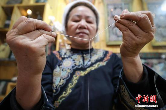 3月1日，韦桃花在马尾上缠绕丝线。水族马尾绣是贵州省黔南州三都水族自治县水族妇女世代传承的一种特殊刺绣技艺，被称为中国刺绣的“活化石”。马尾绣以丝线缠裹马尾并盘在描绘好的花纹轮廓上，再根据轮廓线绣出各种图案，工艺独特、复杂。62岁的韦桃花从小学习马尾绣制作技艺，是中国国家级非物质文化遗产水族马尾绣代表性传承人。50多年来，韦桃花在研究和继承传统马尾绣制作方法的基础上大胆创新，在图案设计、刺绣等工艺方面形成自己独有的制作风格，创作出一批精美独特的马尾绣作品深受消费者喜爱。中新社记者 瞿宏伦 摄