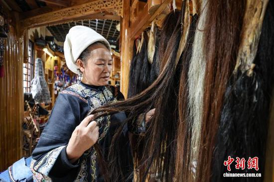 3月1日，韦桃花在筛选马尾。水族马尾绣是贵州省黔南州三都水族自治县水族妇女世代传承的一种特殊刺绣技艺，被称为中国刺绣的“活化石”。马尾绣以丝线缠裹马尾并盘在描绘好的花纹轮廓上，再根据轮廓线绣出各种图案，工艺独特、复杂。62岁的韦桃花从小学习马尾绣制作技艺，是中国国家级非物质文化遗产水族马尾绣代表性传承人。50多年来，韦桃花在研究和继承传统马尾绣制作方法的基础上大胆创新，在图案设计、刺绣等工艺方面形成自己独有的制作风格，创作出一批精美独特的马尾绣作品深受消费者喜爱。中新社记者 瞿宏伦 摄