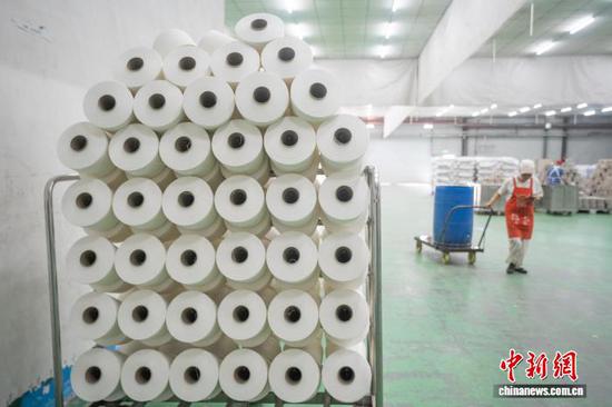 图为贵州省毕节高新区轻纺城内的一家纺织企业车间，工人正在搬运纺纱产品。李安连 摄