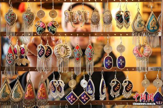 3月1日，韦桃花创新制作的马尾绣耳饰。水族马尾绣是贵州省黔南州三都水族自治县水族妇女世代传承的一种特殊刺绣技艺，被称为中国刺绣的“活化石”。马尾绣以丝线缠裹马尾并盘在描绘好的花纹轮廓上，再根据轮廓线绣出各种图案，工艺独特、复杂。62岁的韦桃花从小学习马尾绣制作技艺，是中国国家级非物质文化遗产水族马尾绣代表性传承人。50多年来，韦桃花在研究和继承传统马尾绣制作方法的基础上大胆创新，在图案设计、刺绣等工艺方面形成自己独有的制作风格，创作出一批精美独特的马尾绣作品深受消费者喜爱。中新社记者 瞿宏伦 摄