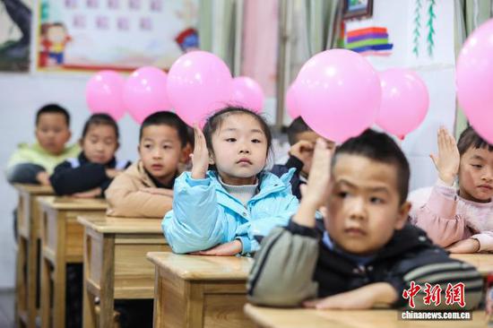 图为小学生在课堂上向老师举手示意。中新社记者 瞿宏伦 摄