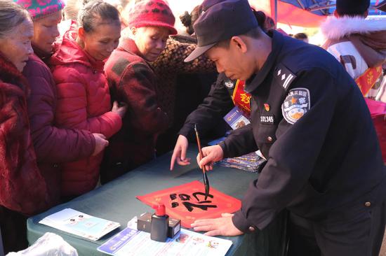图为民警周奋勇坡会现场挥豪书写“福”字,并赠送苗族群众。夏阳春 摄 图为民警周奋勇坡会现场挥豪书写“福”字,并赠送苗族群众。夏阳春 摄