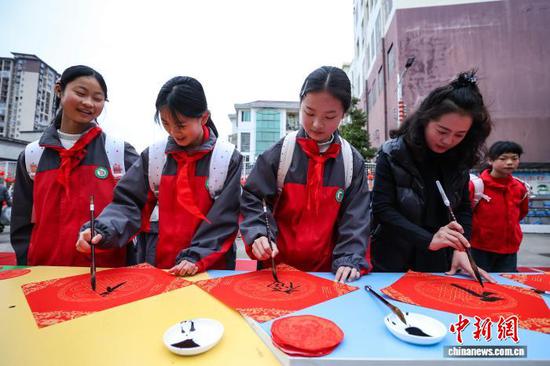 图为老师与小学生一起写福字。中新社记者 瞿宏伦 摄