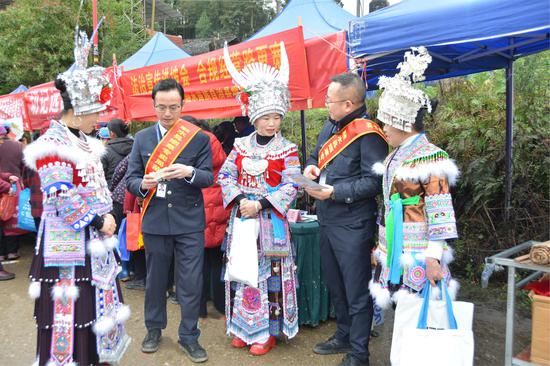 图为“双语”普法人员在坡会现场设立咨询点，与群众互动交流。吴俊鹏 摄