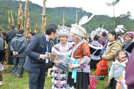 图为“双语”普法人员向赶坡会的未成年人讲解法律知识。吴俊鹏 摄