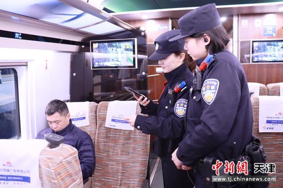 图为北京铁路公安局天津公安处乘警支队乘警张丹彤和宋怡思正在列车车厢内认真开展工作。（北京铁路公安局天津公安处供图）