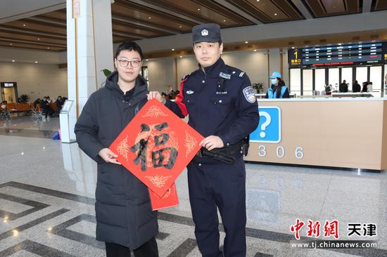 图为春节期间，北京铁路公安局天津公安处沧州站派出所民警给旅客送上自己书写的福字，向出行旅客送上新春祝福。（北京铁路公安局天津公安处供图）