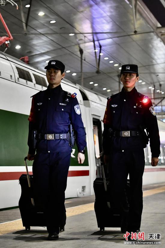 图为夜幕下的天津站站台，两名青年乘警拖着行囊，即将踏上动集列车，开启南北穿梭的平安守护之旅。（北京铁路公安局天津公安处供图）