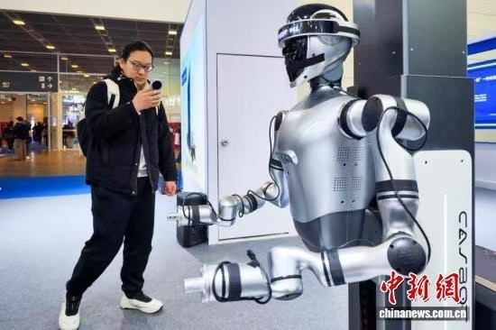 3月18日，天津，观众参观人形机器人。当日，第22届中国（天津）国际装备制造业博览会在国家会展中心（天津）启幕。本届天津工博会以“工业数智转型赋能绿色发展”为主题，汇聚了近800家海内外知名企业参展，设置了机床、机器人、自动化、人工智能、算力基础设施与应用、电子、焊接及切割等展区，集中展示各领域的最新技术、产品和解决方案。中新社记者 佟郁 摄