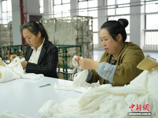 图为3月31日，工人在纺织企业车间的生产线上作业。石小杰  摄