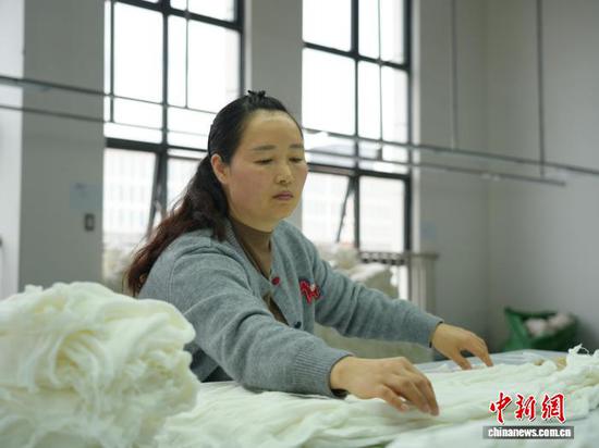 图为3月31日，工人在纺织企业车间的生产线上作业。石小杰  摄
