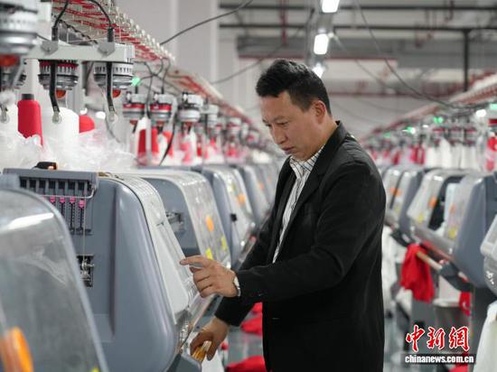 图为3月31日，工人在纺织企业车间的生产线上作业。石小杰  摄