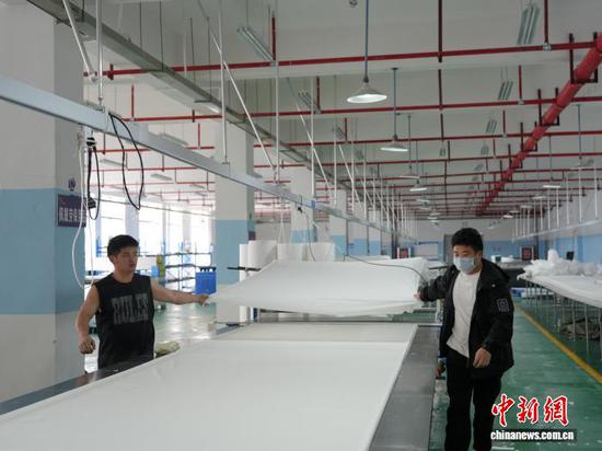 图为3月31日，裁剪工在生产车间里拉布。石小杰 摄