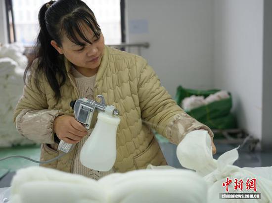 图为3月31日，工人在纺织企业车间的生产线上作业。石小杰  摄