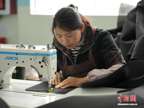 图为3月31日，工人在生产线上用缝纫机缝制车衣。石小杰 摄
