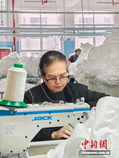 图为3月31日，工人在生产线上用缝纫机缝制车衣。石小杰 摄