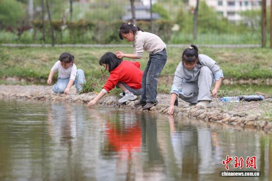 4月1日，贵州省黔南州，学生在贵定县金海乐园人造池边进行科普活动。当日，贵州中小学生迎来首个春假，为丰富学生假期生活，贵州各地因地制宜推出系列多彩活动，让学生乐享春假时光。中新社记者 瞿宏伦 摄