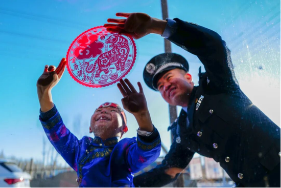 民警与辖区群众一同贴窗花。来源：博州移民管理之声微信公众号e