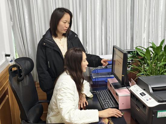 图为纪检监察干部一对一指导员工操作“数字纪检”平台。黄心力 摄