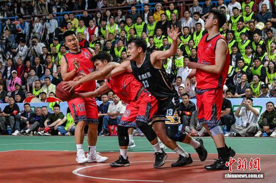 4月11日晚，凯里市代表队(黑衣)和沿河自治县代表队球员在比赛中。中新社记者 瞿宏伦 摄