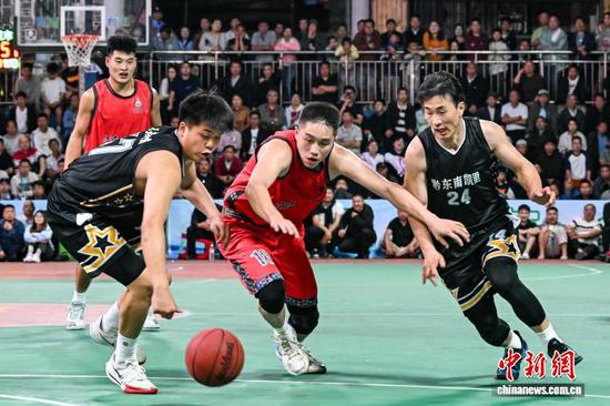 4月11日晚，凯里市代表队(黑衣)和沿河自治县代表队球员在比赛中。中新社记者 瞿宏伦 摄