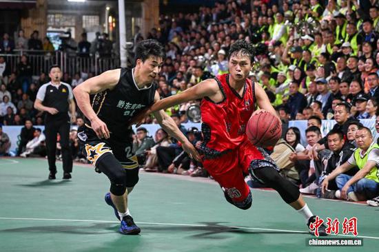 4月11日晚，凯里市代表队(黑衣)和沿河自治县代表队球员在比赛中。中新社记者 瞿宏伦 摄