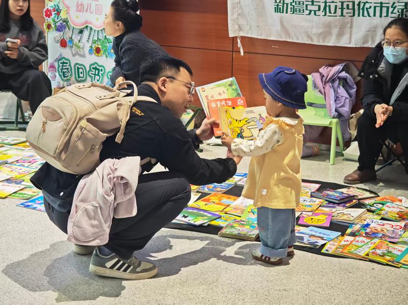 閱讀接力站圖書漂流集市內(nèi)，一位父親正在為孩子挑選童書?？死斠廊诿接浾?侯婧婧 攝