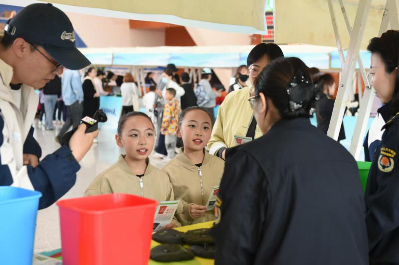 工作人員正通過互動(dòng)體驗(yàn)的方式，向?qū)W生們普及垃圾分類知識(shí) ?？死斠廊诿接浾?王兆國 攝