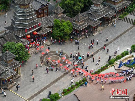 4月19日，贵州省黎平县肇兴侗寨的侗族群众向游客展示盛装巡游。龙建睿 摄