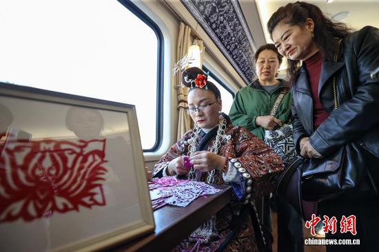 图为多彩贵州号旅游专列内的苗族剪纸展示吸引旅客。