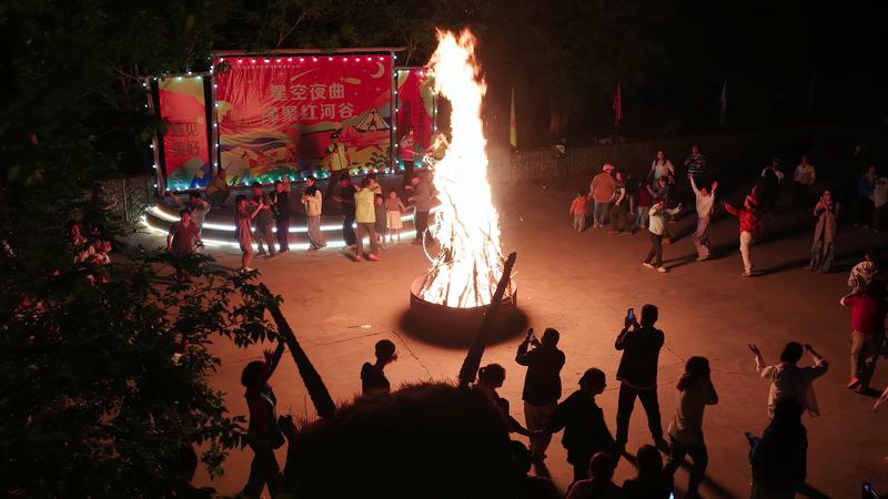 夜暮降临游客围着篝火跳舞狂欢。
