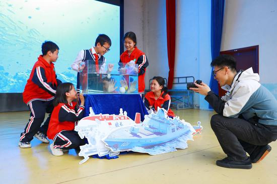 合肥工业大学研究生支教团成员正在记录学生做科学实验。谢达意摄
