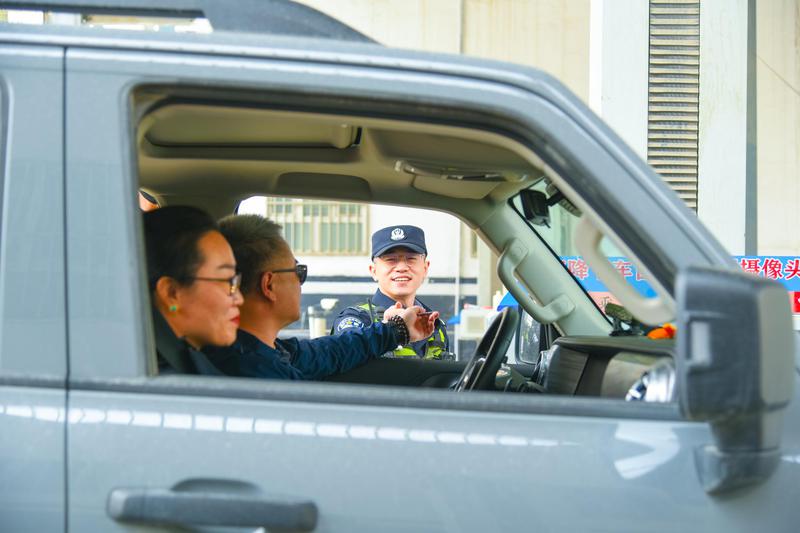 5月3日，库地边境检查站民警何朋亮热情服务过往旅客。李斌摄