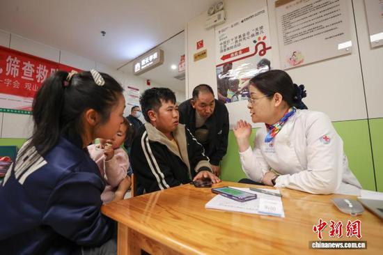 图为医护人员在为孩子家长讲解免费手术治疗相关事项。中新社记者 瞿宏伦 摄