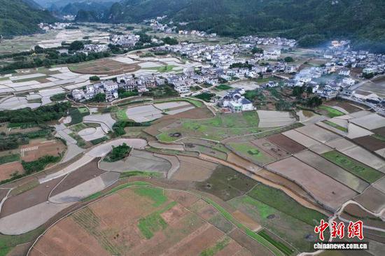 5月13日，航拍贵州省黔西南布依族苗族自治州兴义市万峰林水田。时下，万峰林水田迎来注水、插秧时节。从空中俯瞰，水田宛如天然“调色板”，与山峰、河流、村寨等融为一体，呈现出别样的田园风景。(无人机照片)中新社记者 瞿宏伦 摄