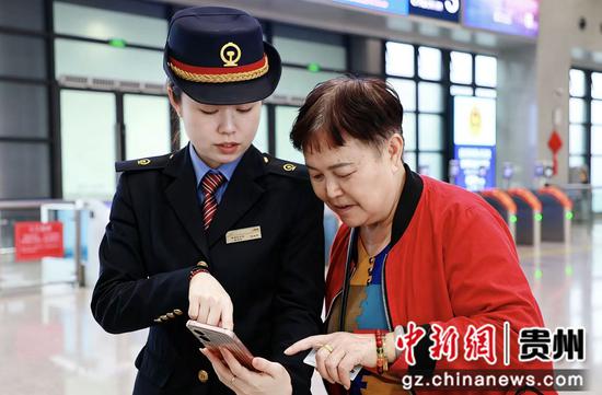 5月15日，在黔西高铁站拍摄的工作人员正在指导老年乘客使用手机购票。