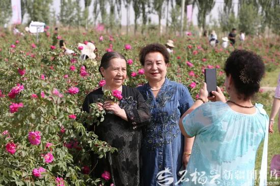 5月16日，以“花开沙漠·香满于田”为主题的第九届玫瑰风情文化旅游活动在于田县阿热勒乡万方村火热举行，图为当地游客在花海中合影留念。石榴云/新疆日报记者 拍热扎提·阿不都 摄