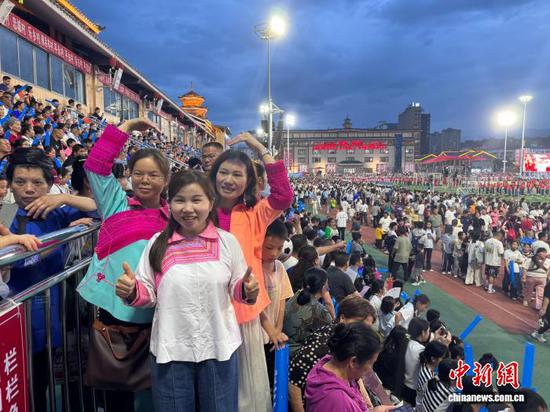 图为5月16日晚，贵州“村超”冠军赛现场，球迷身着民族服饰拍照“打卡”。中新网记者 袁超 摄