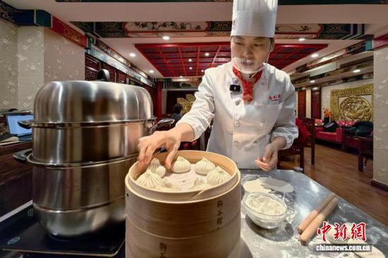 狗不理集团面品部部长、第九代传承人赵惠芬在狗不理天津水上北路旗舰店为食客制作狗不理包子。中新社记者 佟郁 摄 狗不理集团面品部部长、第九代传承人赵惠芬在狗不理天津水上北路旗舰店为食客制作狗不理包子。中新社记者 佟郁 摄