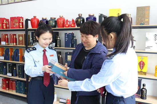 国家税务总局金沙县税务局组织青年干部对涉及出口业务的纳税人缴费人进行走访问需。图为青年干部正在了解贵州金派国际贸易有限公司出口的白酒产品之一。（朱泫粼 摄）