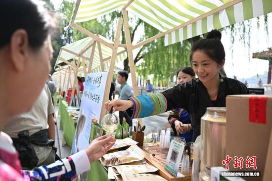 5月21日是国际茶日，“干净黔茶·全球共享”5·21国际茶日主题活动在北京北海公园拉开帷幕。活动上，贵州茶企对贵州茶进行推介，吸引游园市民品尝贵州生态茶以及抹茶产品。图为工作人员为市民倒茶。中新社记者 赵文宇 摄