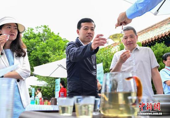 5月21日是国际茶日，“干净黔茶·全球共享”5·21国际茶日主题活动在北京北海公园拉开帷幕。活动上，贵州茶企对贵州茶进行推介，吸引游园市民品尝贵州生态茶以及抹茶产品。图为市民在现场品茶。中新社记者 赵文宇 摄