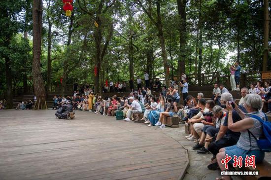 图为游客在观看传统镰刀剃头。吴德军 摄